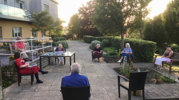 photo of people sitting outside the hospital having a trustee meeting being socially distant