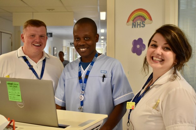 three people smiling and looking to camera